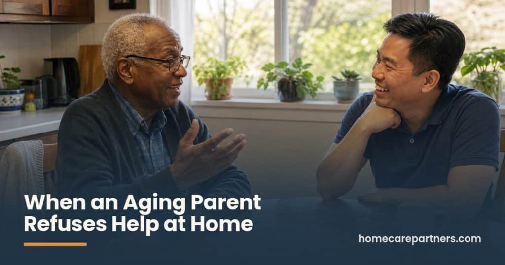 An older man and his caregiver laugh together over coffee and a jigsaw puzzle at a sunny kitchen table.
